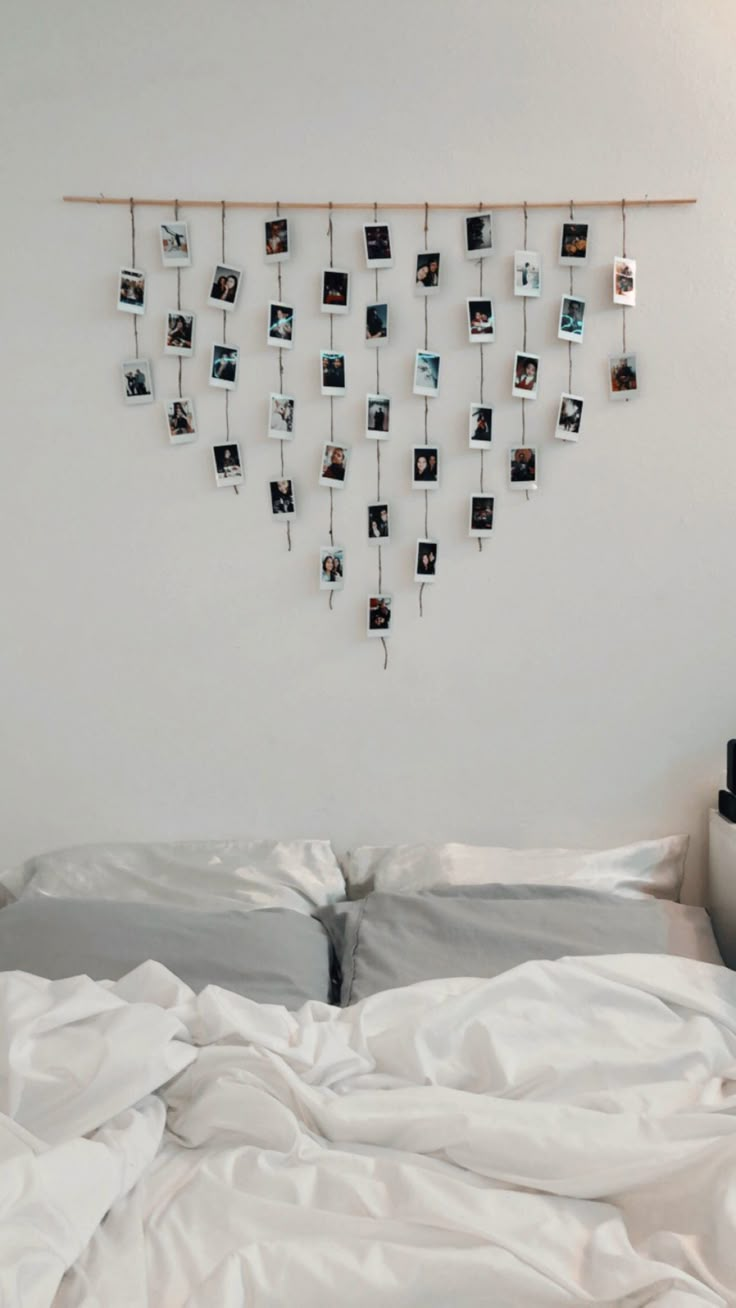 an unmade bed with white sheets and pictures hanging on the wall