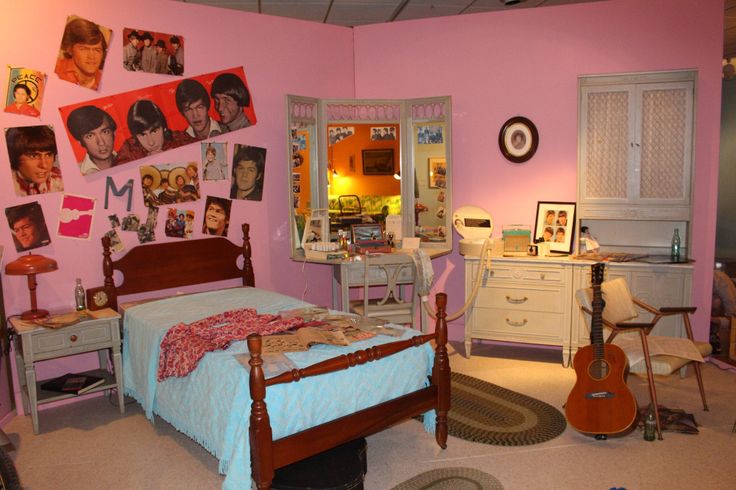 a bedroom decorated in pink and white with pictures on the wall above the bed, desk, and guitar