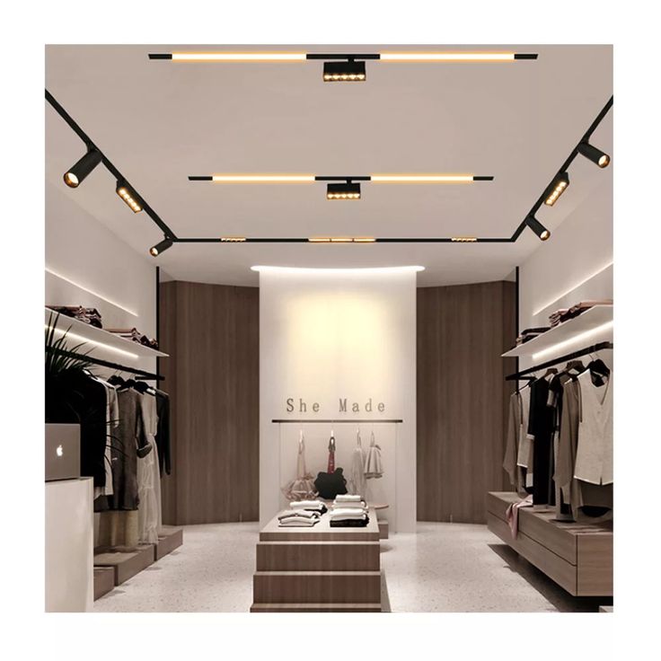 an empty store with clothes on display and lights above the clothing racks in front of them