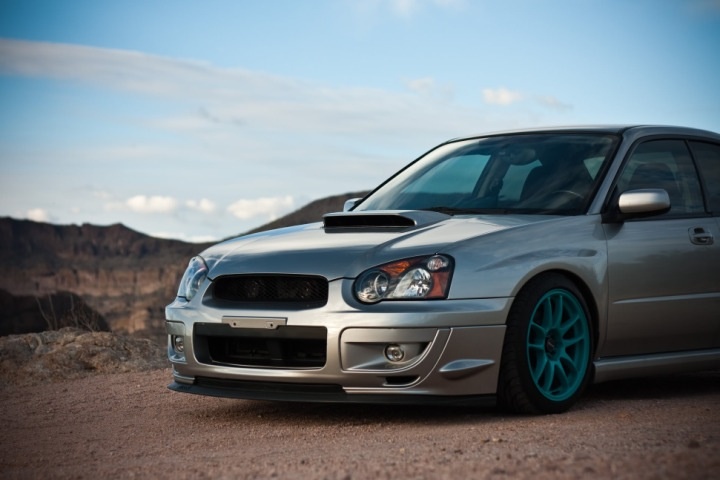 a silver car parked on top of a dirt road