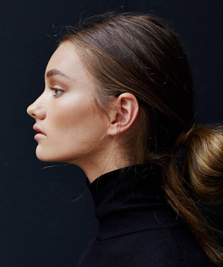 a woman with her hair in a high pony tail ponytail wearing a black turtle neck sweater