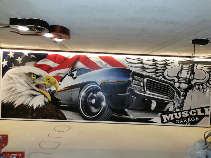 an eagle and american flag painted on the side of a wall in a car garage