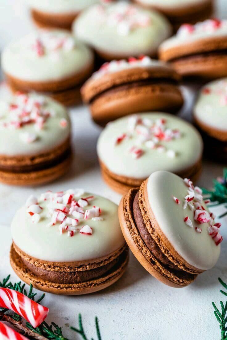 several cookies with white frosting and sprinkles are on a table next to candy canes