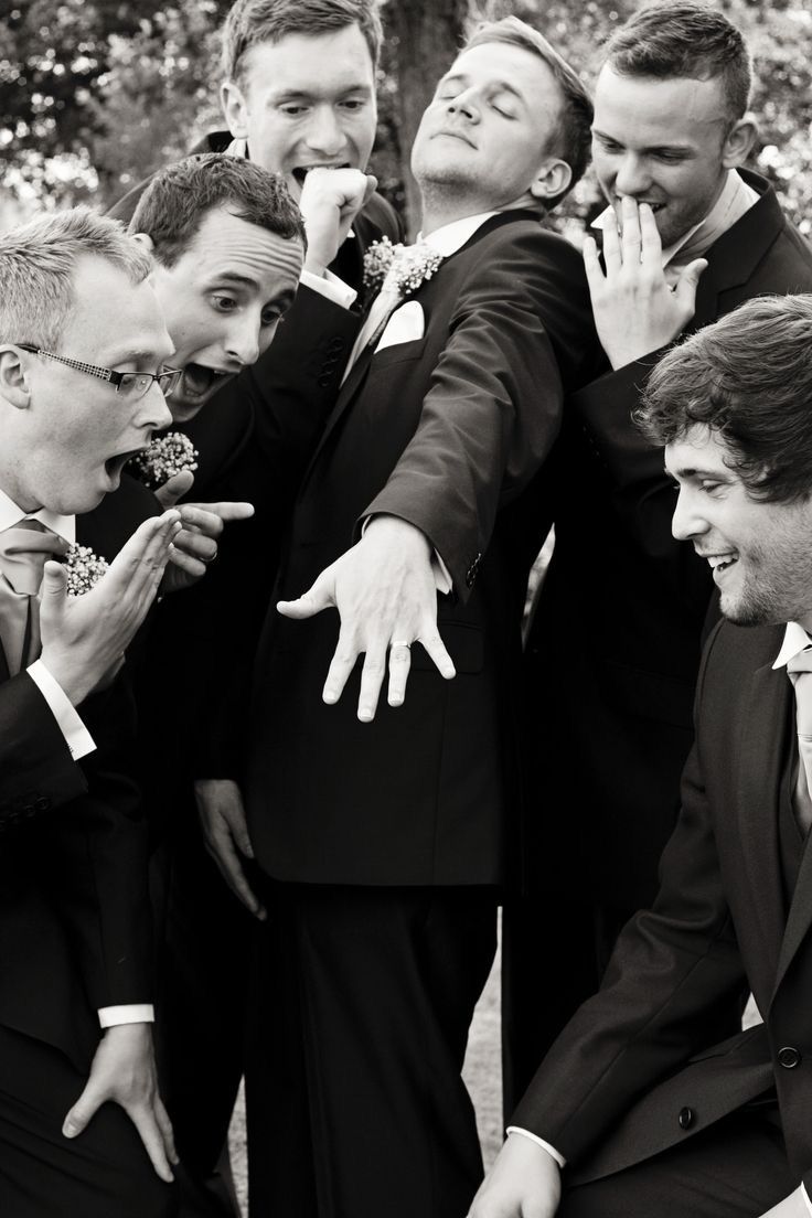 a group of men standing next to each other wearing suits and ties with their hands in the air