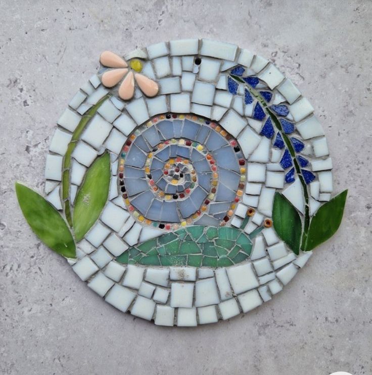 a mosaic tile design with flowers and leaves on it's side, in the shape of a snail