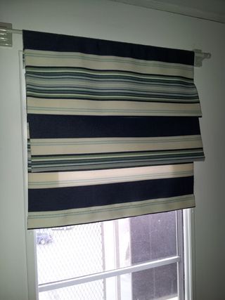 a window with a black and white striped blind in front of a window sill