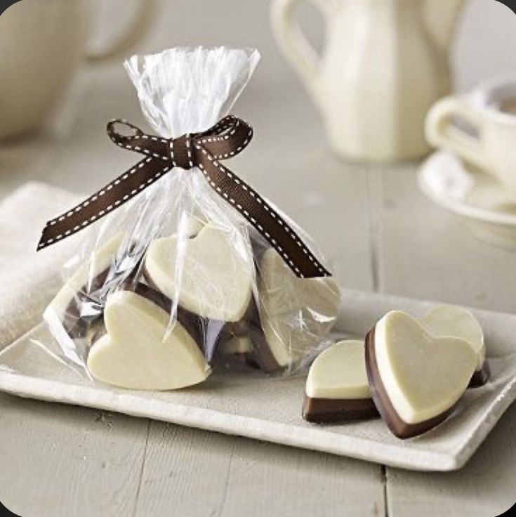 heart shaped cookies wrapped in cellophane and tied with ribbon on a white tray