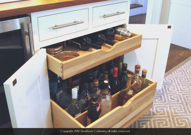 an open cabinet with bottles and glasses in it