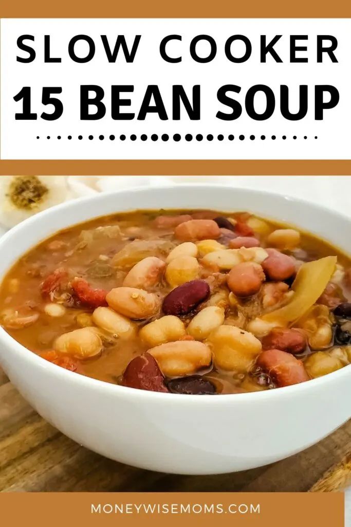 a white bowl filled with bean soup on top of a wooden cutting board and text overlay reads, slow cooker 15 bean soup