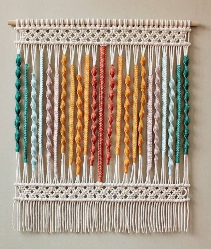 a wall hanging made out of macrame yarn and colorful beads on a wooden stick