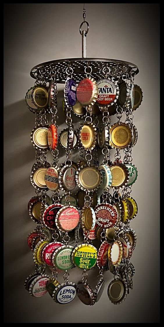 a metal rack with many bottle caps hanging from it's sides and a light fixture in the middle