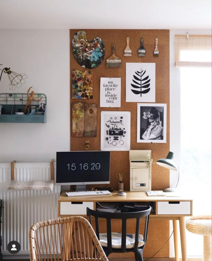 a desk with a computer on top of it next to a wall covered in pictures