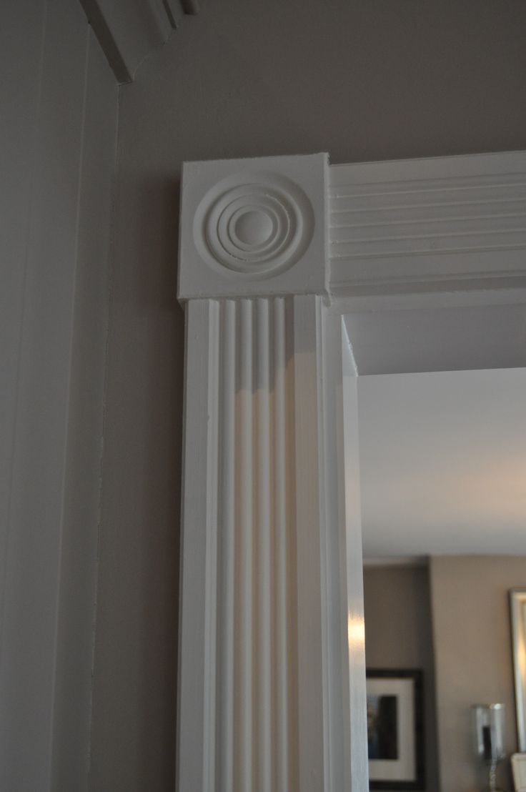 the corner of a white column with a mirror in the background