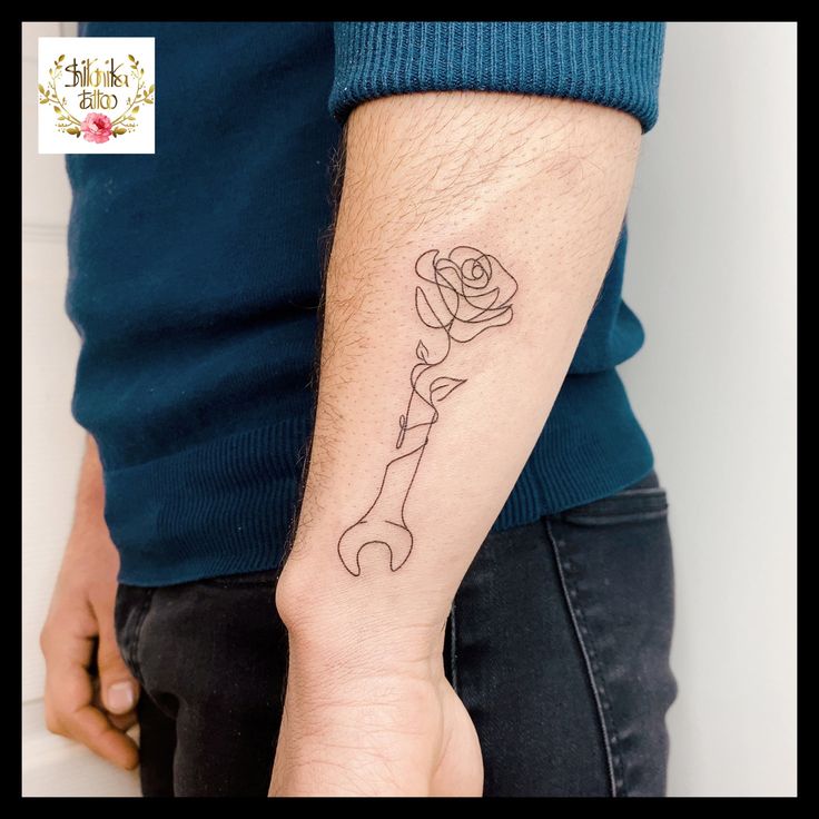 a man with a tattoo on his arm holding a wrench in one hand and a rose in the other