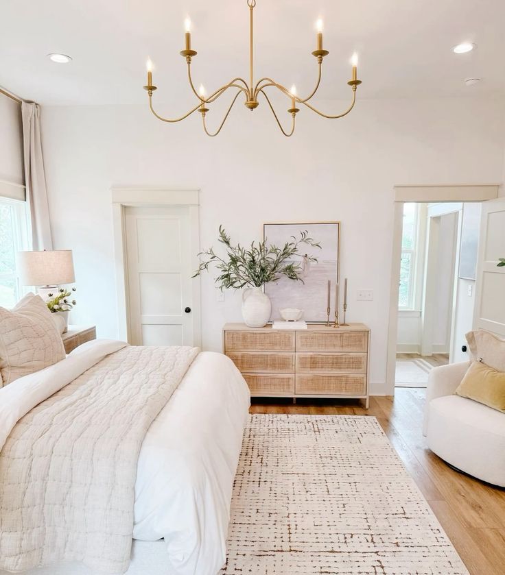 a large white bed sitting in a bedroom on top of a hard wood flooring