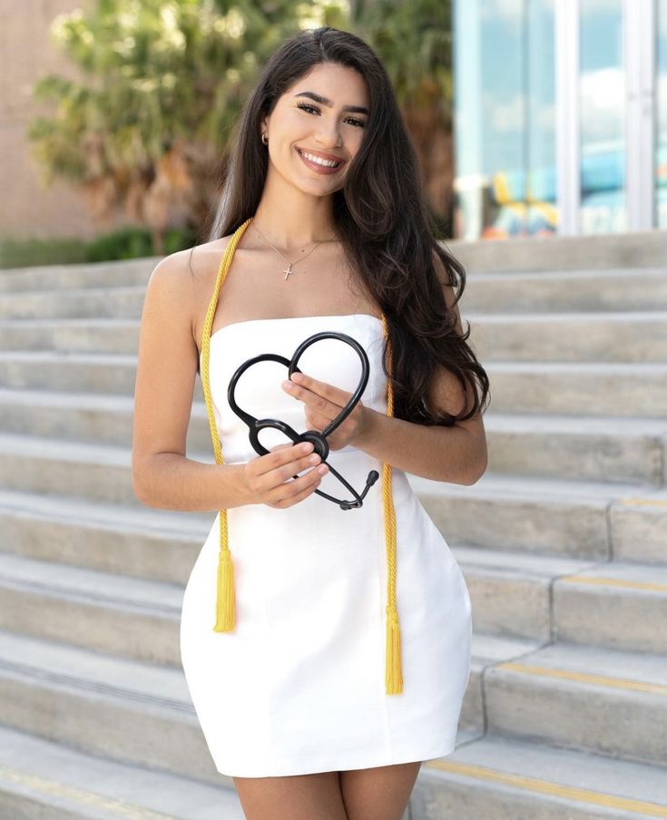 a woman in a white dress holding a pair of scissors and smiling at the camera