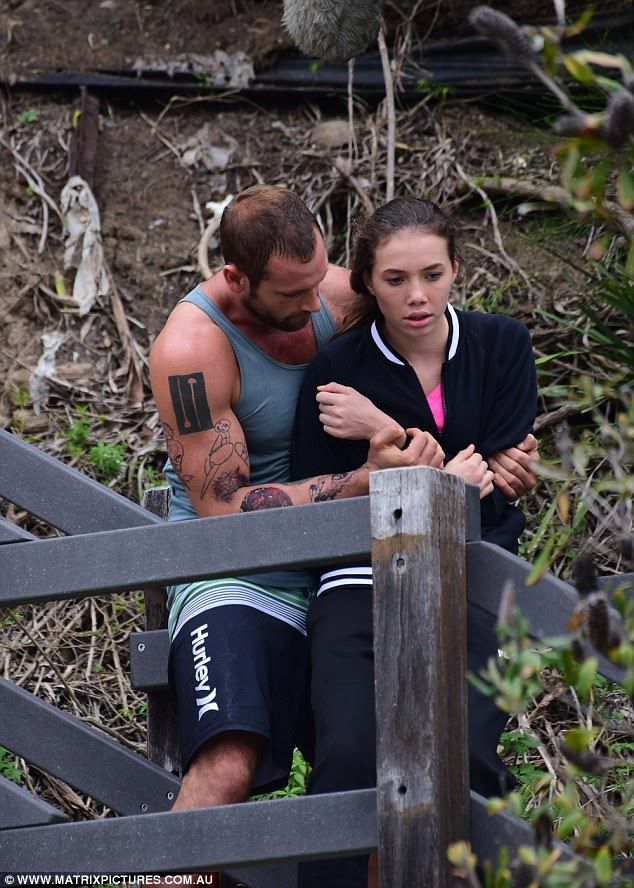 a man and woman sitting on top of a wooden bench