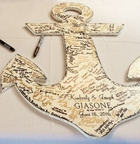 a wooden anchor with writing on it and a pen next to it, sitting on a table