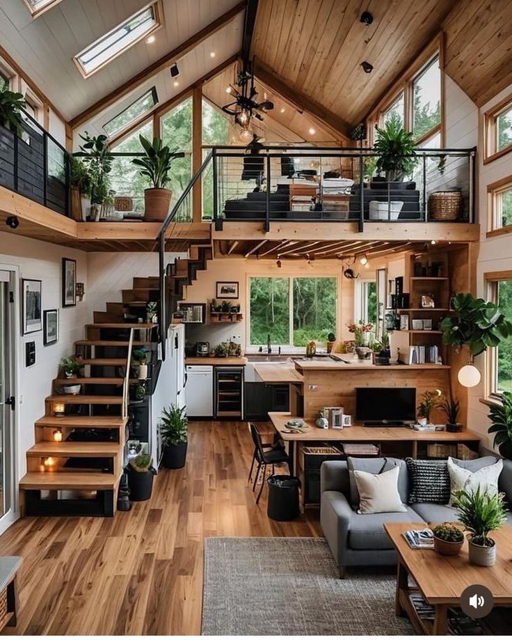 a living room filled with furniture and lots of windows next to a staircase leading up to a loft