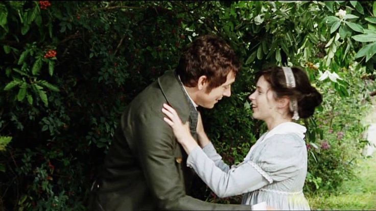 a man and woman standing next to each other in front of trees