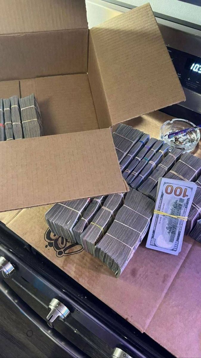 a pile of money sitting on top of a table next to a cardboard box filled with silver dollar bills