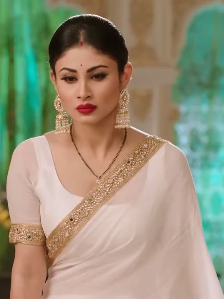 a woman in a white sari and gold jewelry