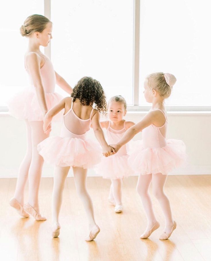 three young ballerinas in pink tutues are holding hands with each other