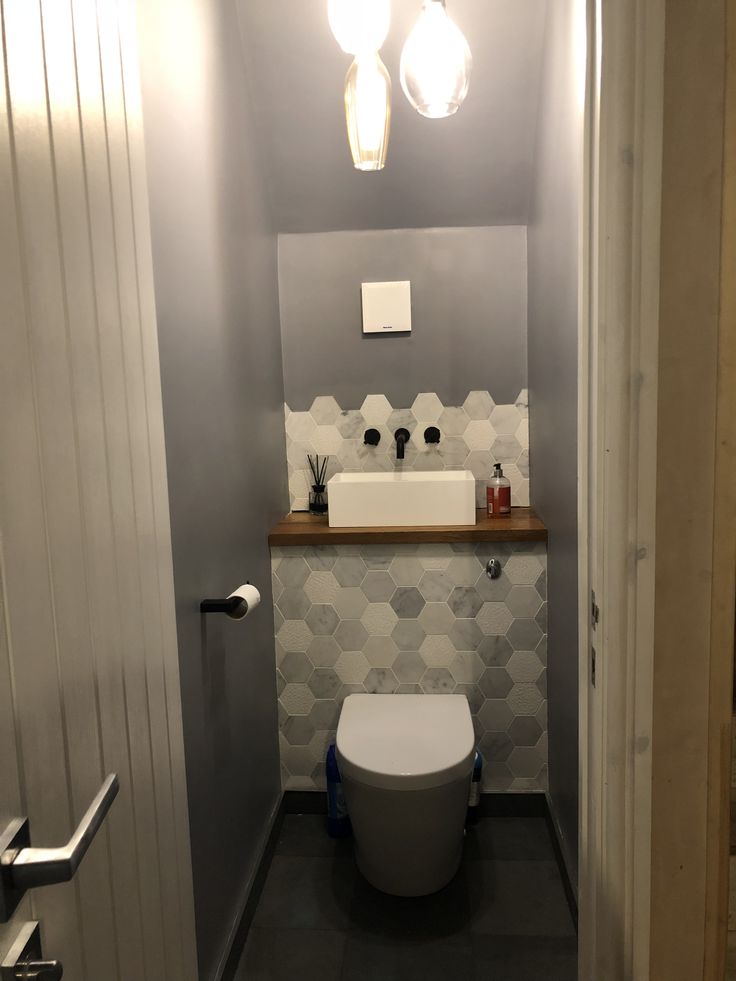 a white toilet sitting in a bathroom next to a sink and light bulb above it