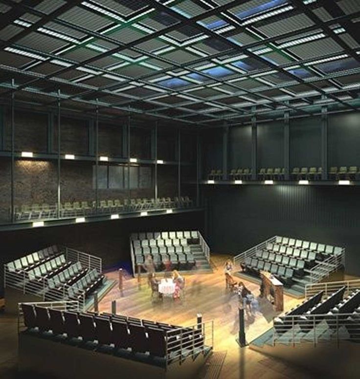 an empty auditorium with rows of seats and people standing on the stage in front of them