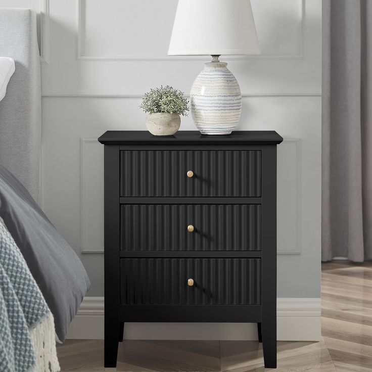 a night stand with two drawers and a white vase on the nightstand next to it