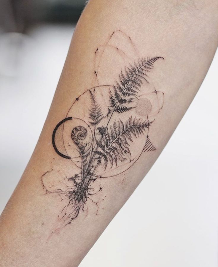 a tattoo on the arm of a person with a fern and moon in it's center