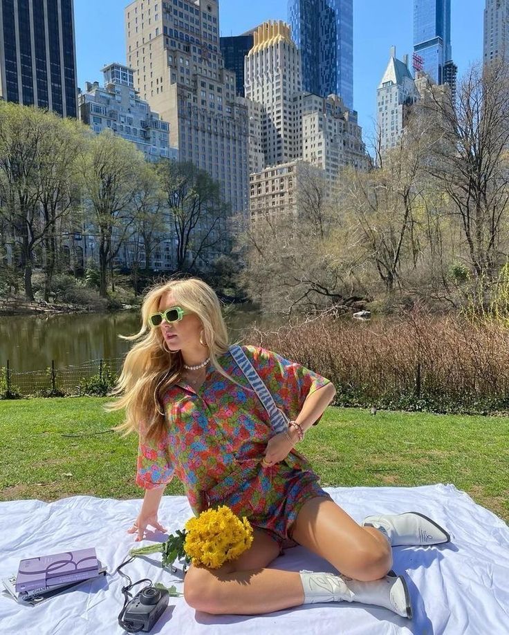 a woman sitting on top of a blanket in front of a city skyline holding a guitar