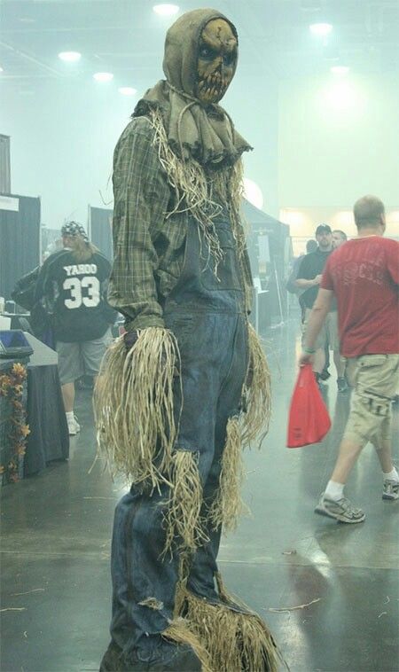 a scarecrow is standing in the middle of a room with people walking around it