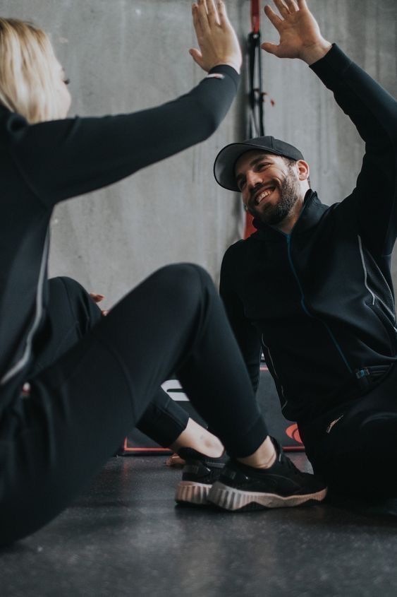 a man and woman sitting on the ground with their hands in the air