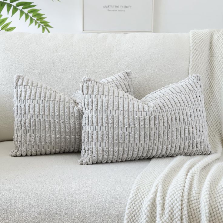 two pillows sitting on top of a white couch