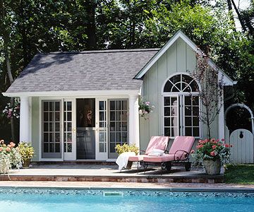 a small pool house next to a swimming pool with chaise lounges near it