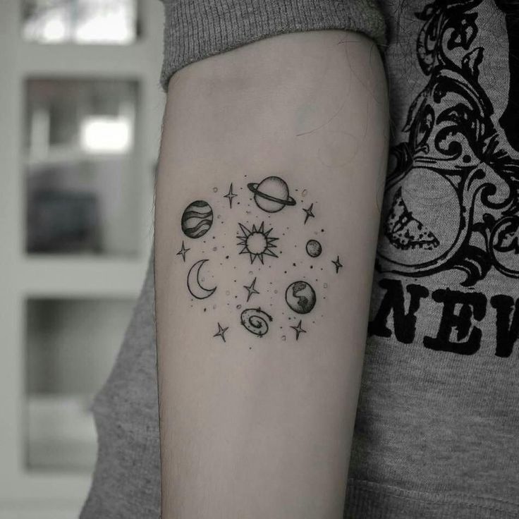 a woman's arm with a tattoo on it that has planets and stars in the middle