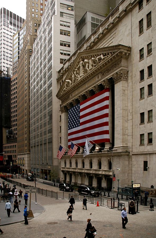 people are walking around in front of a building with an american flag on the wall