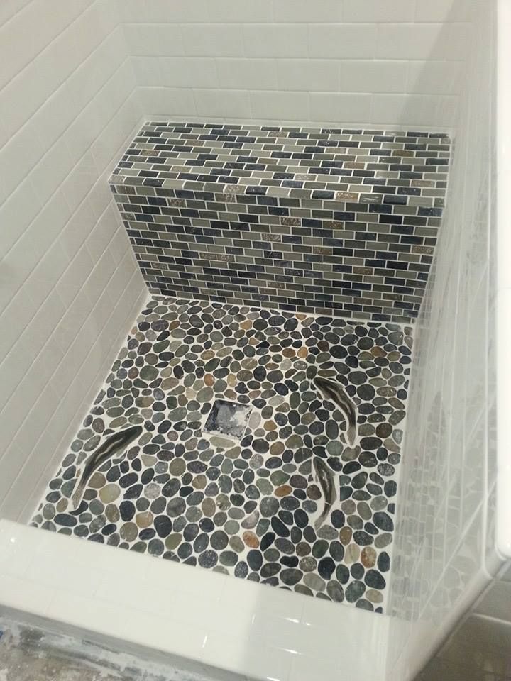 a bath tub with a mosaic tile floor and shower wall next to it's door