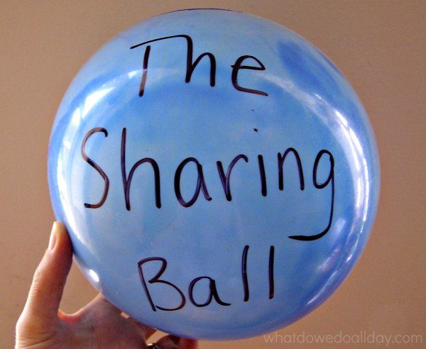 a person holding up a blue balloon with the words, the sharing ball written on it