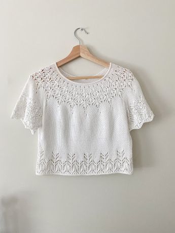 a white crop top hanging on a wall