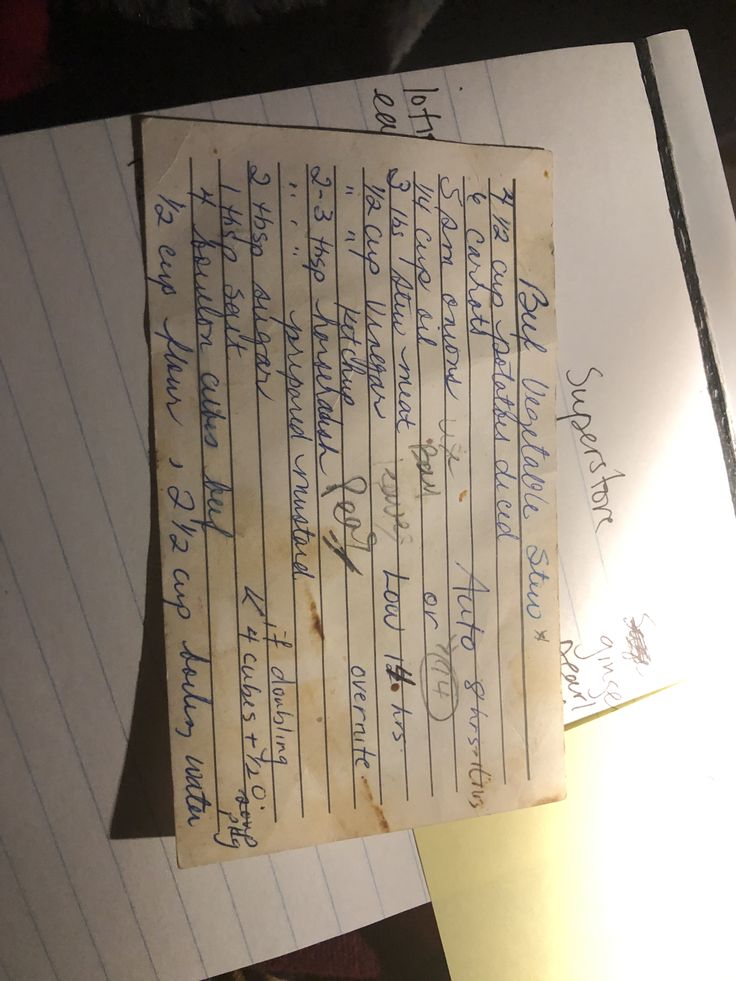 an old piece of paper with writing on it sitting on top of a desk next to a lamp