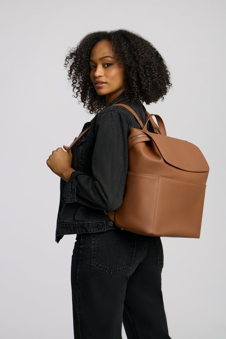 a woman carrying a brown leather bag on her back, with the top part of her body visible