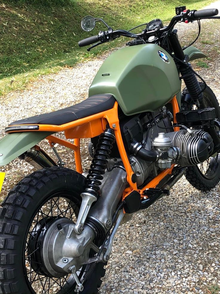 an orange and green motorcycle parked on gravel