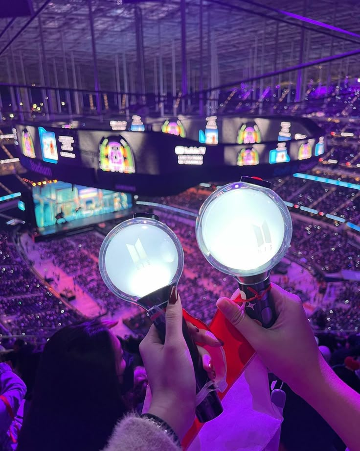 two people holding up some lights in front of a crowd at a sporting event,