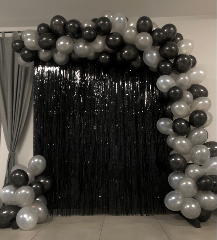 a black and white balloon arch with silver balloons