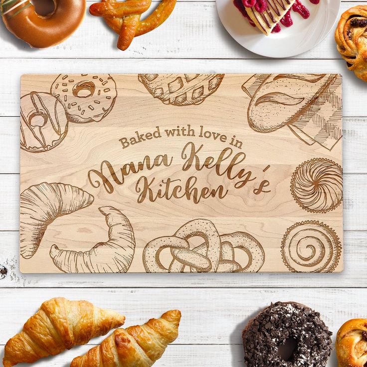 a wooden cutting board with the words baked with love on it surrounded by pastries