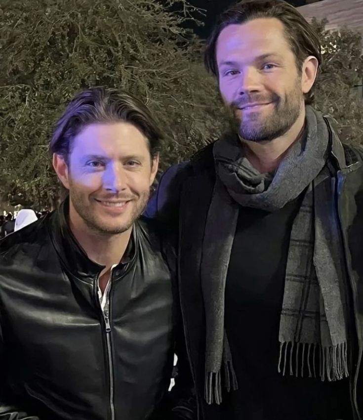 two men standing next to each other smiling