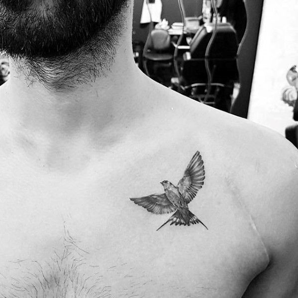 a black and white photo of a man's chest with a bird tattoo on it