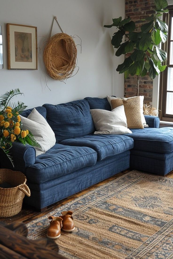 a living room with a blue couch, rug and potted plant in the corner